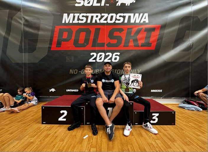 Łukasz Skarżyński, główny trener sportów walki Stowarzyszenia BESTIOS, na podium Mistrzostw Polski SOLT 2026 w Warszawie z dwoma medalistami klubu